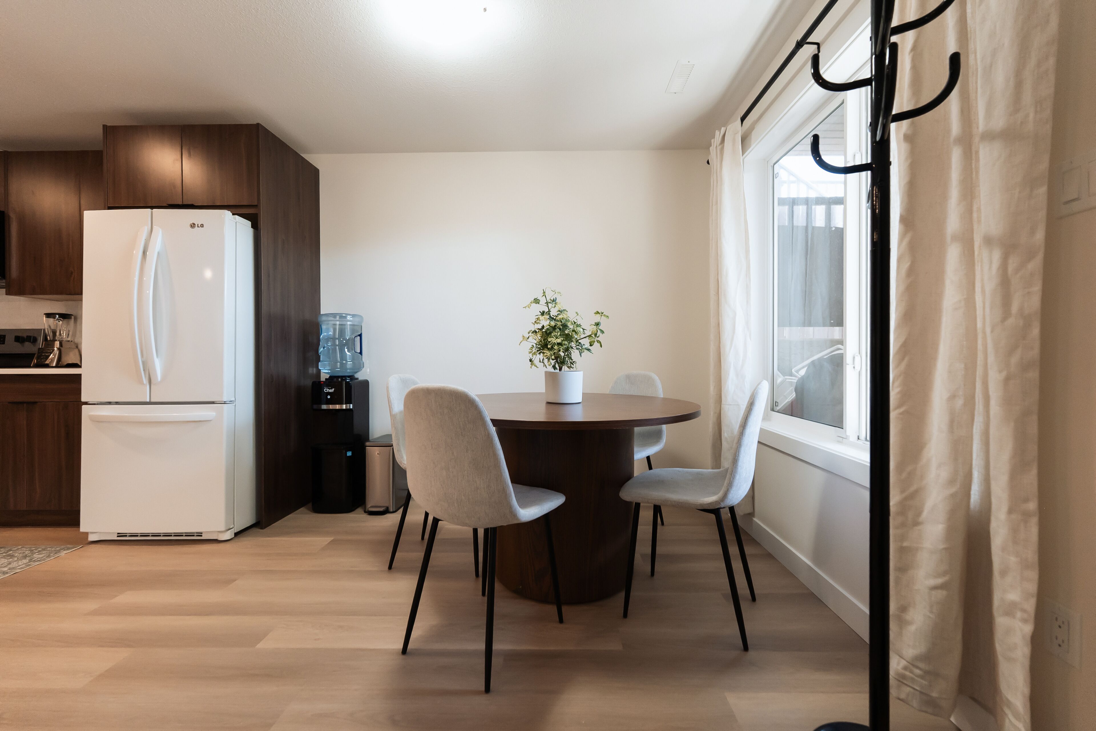 A modern kitchen with a white LG refrigerator, a water dispenser, and a dining table with four chairs.