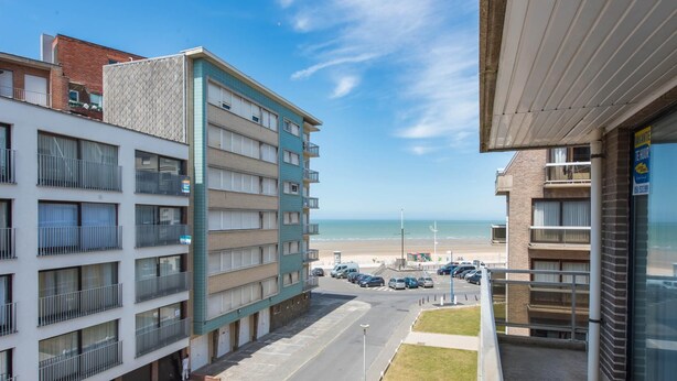 Ett hotell med flera våningar, balkonger, en parkeringsplats och utsikt över stranden.