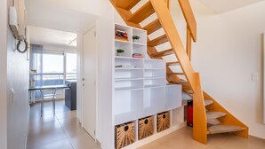 Een modern appartement met een houten trap, een keukenhoek en een eethoek.
