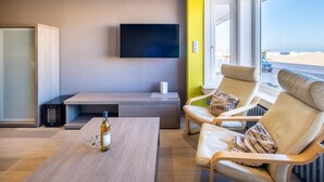 A modern living room with a flat-screen TV, comfortable seating, a coffee table, and a bottle of alcohol.