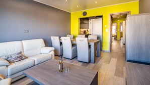 A modern living room with a sofa, coffee table, and dining area.