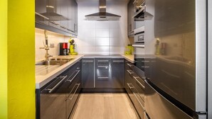 A modern kitchen with stainless steel appliances, a central island, and a bright yellow accent wall.