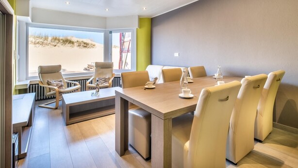 A modern meeting room with a large table, comfortable chairs, and a view of the beach.
