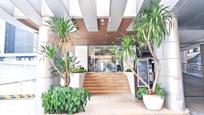 A modern building entrance with a staircase, potted plants, and a vending machine. - Harmony Living Condominium (Bangkok)