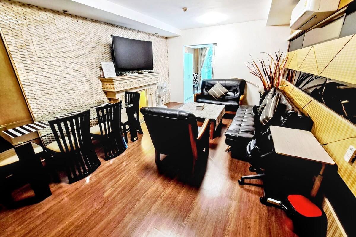 A living room with a flat-screen TV, a sofa, a coffee table, and a fireplace.