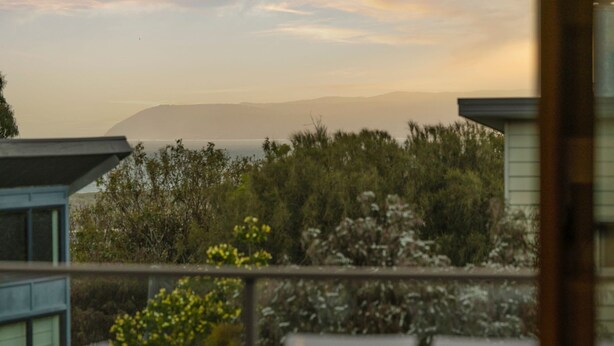 A view from a balcony overlooking a natural landscape with trees and hills in the distance. - Idyllic Aireys Retreat - where ocean & hills meet (Aireys Inlet)