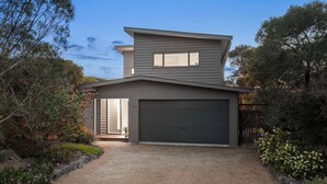A modern two-story house with a garage, surrounded by landscaped gardens and trees. - Idyllic Aireys Retreat - where ocean & hills meet (Aireys Inlet)