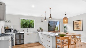 Een moderne keuken met witte kasten, een groot eiland en hanglampen.