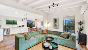 Een moderne woonkamer met een groene modulaire bank, een ronde salontafel, en een keuken op de achtergrond.