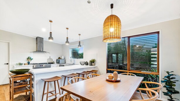 Een moderne keuken met een centraal eiland, hanglampen en een groot raam met uitzicht.
