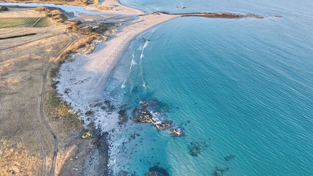 An aerial view of a coastal area with a beach, rocky shoreline, and agricultural fields. - Blacksmith's Cottage at Lisdillon Estate (Little Swanport)