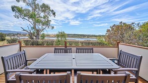 A patio with a table and chairs, overlooking a natural landscape with trees and a body of water. - Blacksmith's Cottage at Lisdillon Estate (Little Swanport)