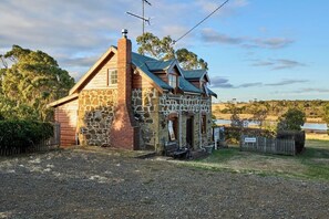 A stone and wood building with a chimney, a small porch, and a sign reading 'Blacksmiths.' - Blacksmith's Cottage at Lisdillon Estate (Little Swanport)