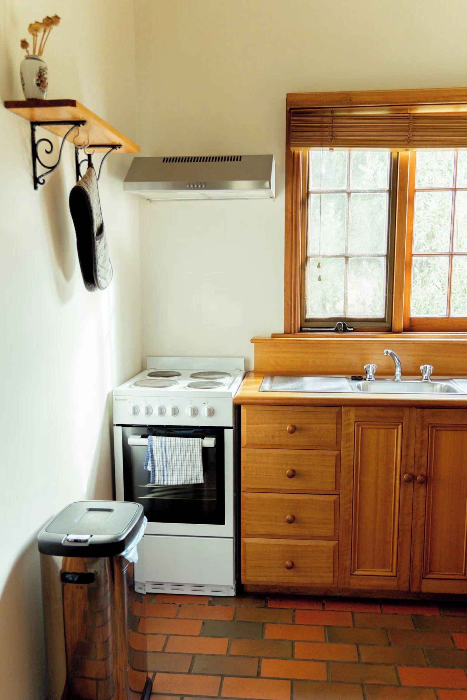 Une cuisine équipée d’une cuisinière, d’un four, d’un évier, de meubles de rangement en bois et d’une fenêtre.
