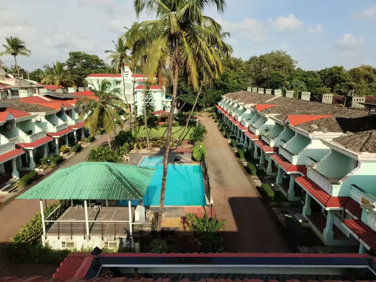 A resort with multiple bungalow-style buildings, a central swimming pool, and lush greenery.