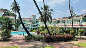 A resort with multiple buildings, a swimming pool, and palm trees.