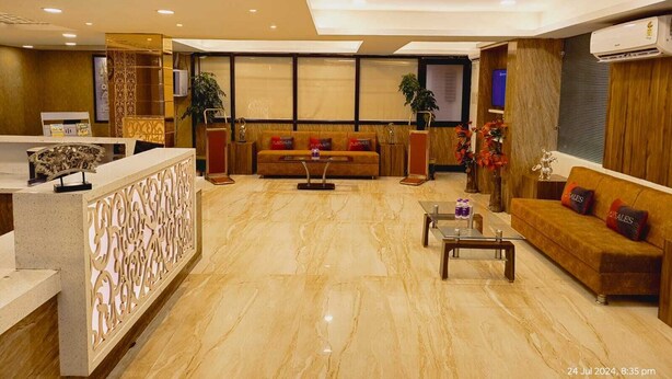 A spacious lobby with a reception desk, a sofa set, a coffee table, and a decorative plant. - Hotel Abhinandan (Bhopal)