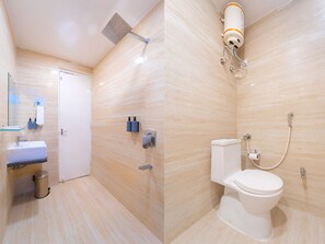 A modern bathroom with a shower, toilet, sink, and a glass partition. - Hotel Abhinandan (Bhopal)