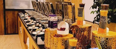 A buffet setup with various food items and beverages, including nuts and a bowl of what appears to be a fruit salad.
