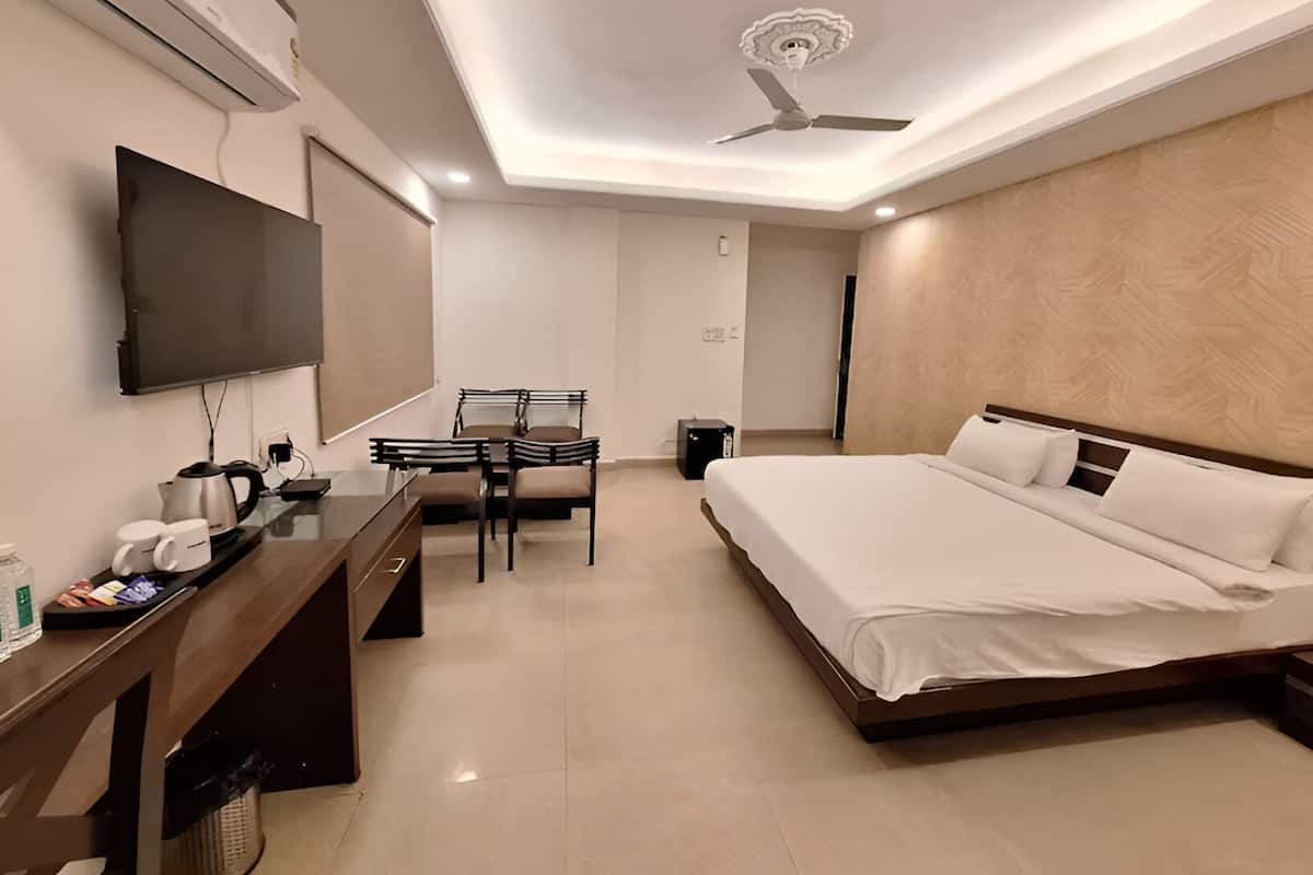 A hotel room with a bed, a desk with a chair, a television, and a ceiling fan.