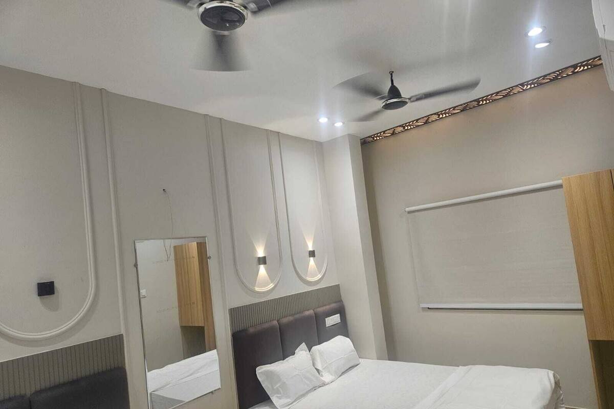 Ein modernes Hotelzimmer mit einem großen Bett, einem Nachttisch, einem Spiegel und einem Deckenventilator.