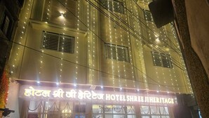 Das Hotel Shree Ji Heritage mit einer mehrsprachigen Beschilderung, großen Fenstern und einem gut beleuchteten Eingang.
