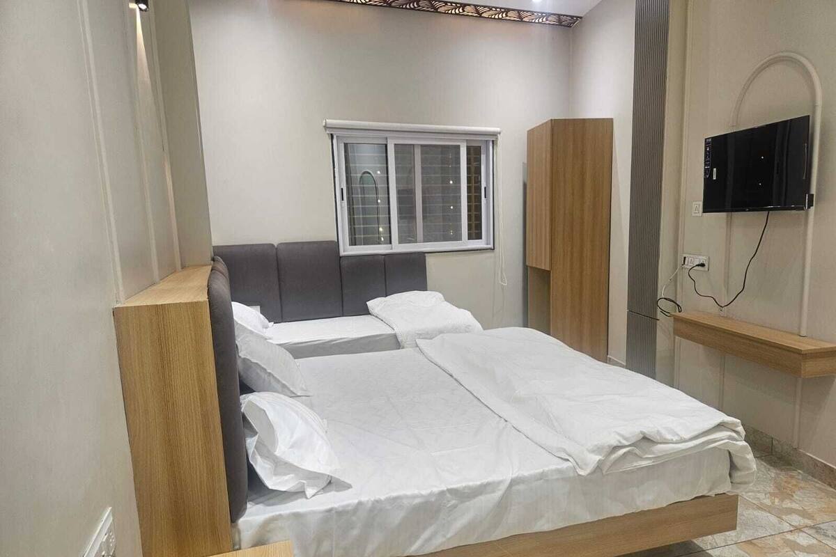Ein Schlafzimmer mit Bett, Fenster, Fernseher und Nachttisch.