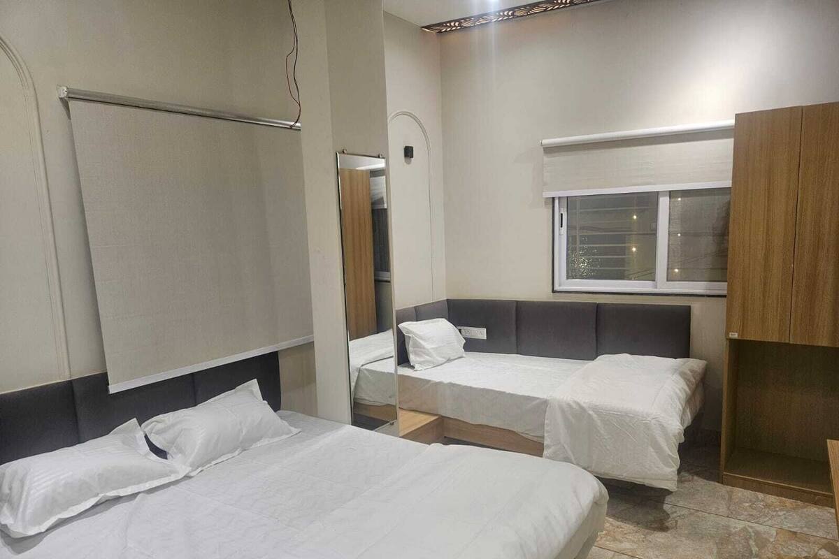 Ein Hotelzimmer mit zwei Einzelbetten, einem Fenster und einem Spiegel.