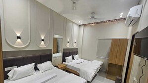 Ein Hotelzimmer mit zwei Betten, einem Kleiderschrank, einem Spiegel und einem Fernseher.