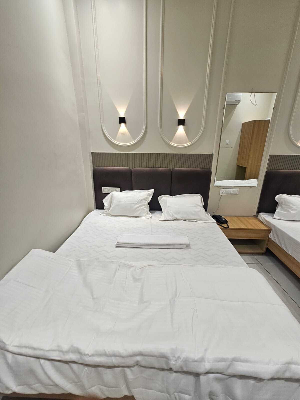 A hotel room with a large bed, two bedside tables, a mirror, and wall-mounted lighting.