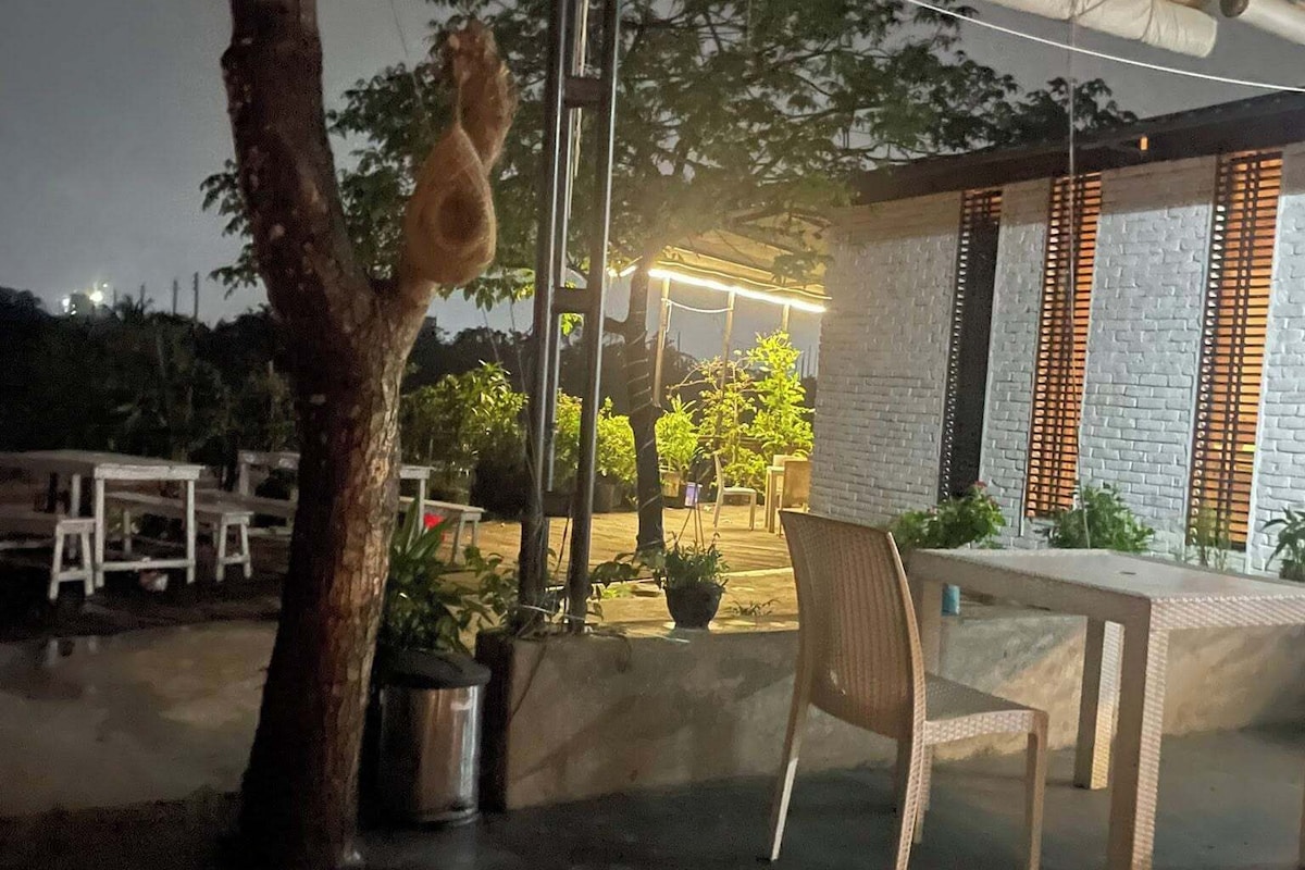 An outdoor seating area with a table and chairs, a tree, and a hanging light fixture.