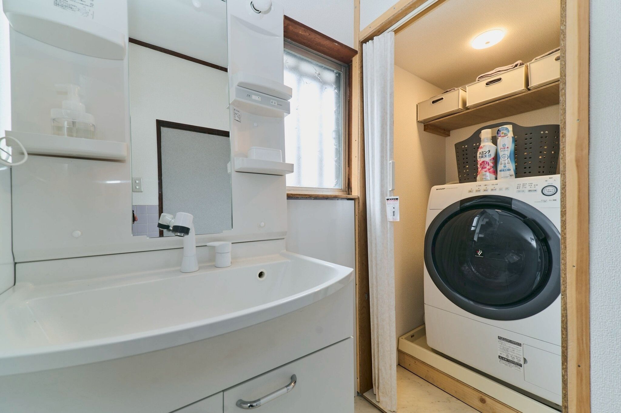 A compact bathroom with a sink, mirror, and a washing machine.