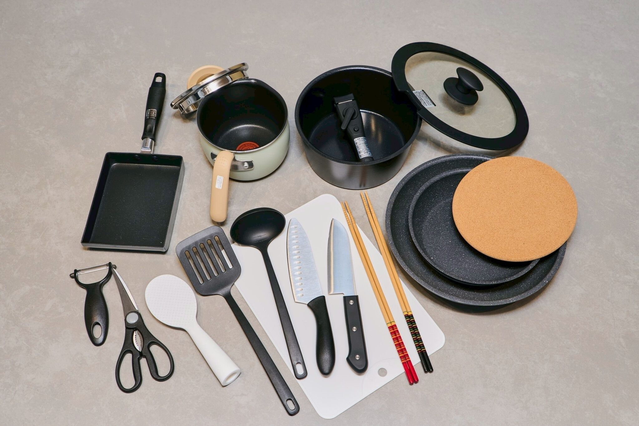 A variety of kitchen utensils and cookware laid out on a flat surface.