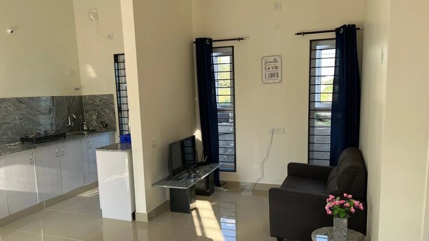 Quarto moderno com cama, um espaço de estar pequeno, cozinha e janela com cortinas.