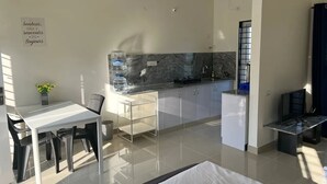 Uma cozinha moderna com bancada de mármore, armários brancos e um espaço de jantar com mesa e cadeiras.