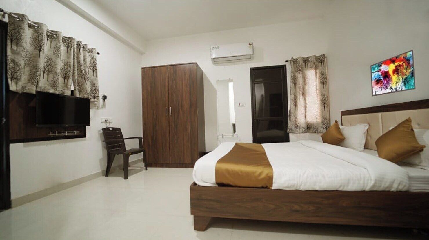 A bedroom with a bed, a wardrobe, a chair, a TV, and a painting on the wall.