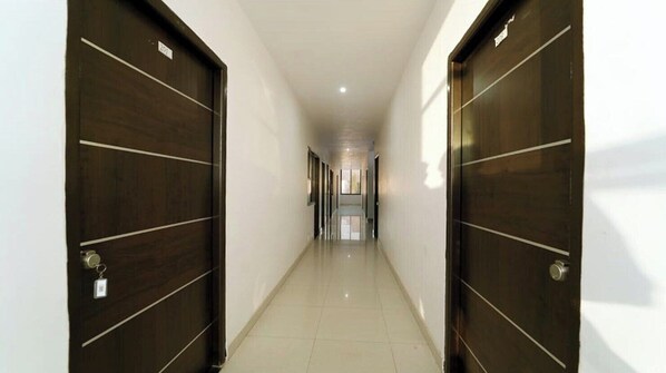 A hallway with two dark wooden doors on either side, leading to a room with a view. - Hotel Decent Inn (Udaipur)