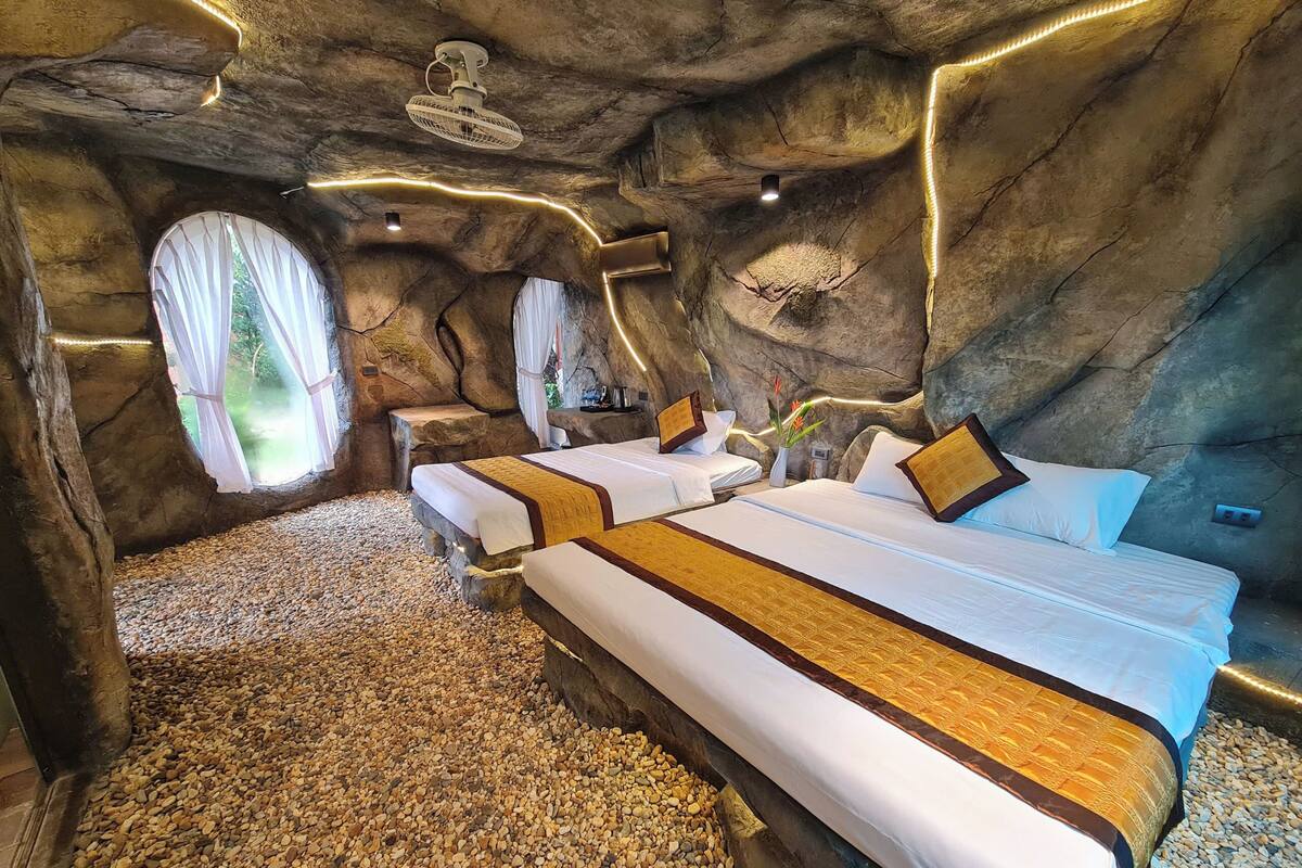 Una habitación con dos camas, un ventanal grande y un ventilador.