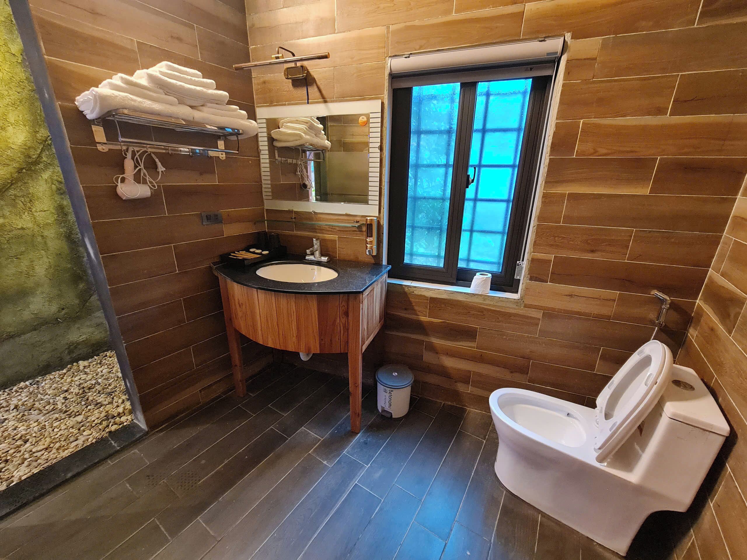 Une salle de bain avec un meuble-lavabo en bois, un évier, des toilettes et une fenêtre donnant sur un beau paysage.