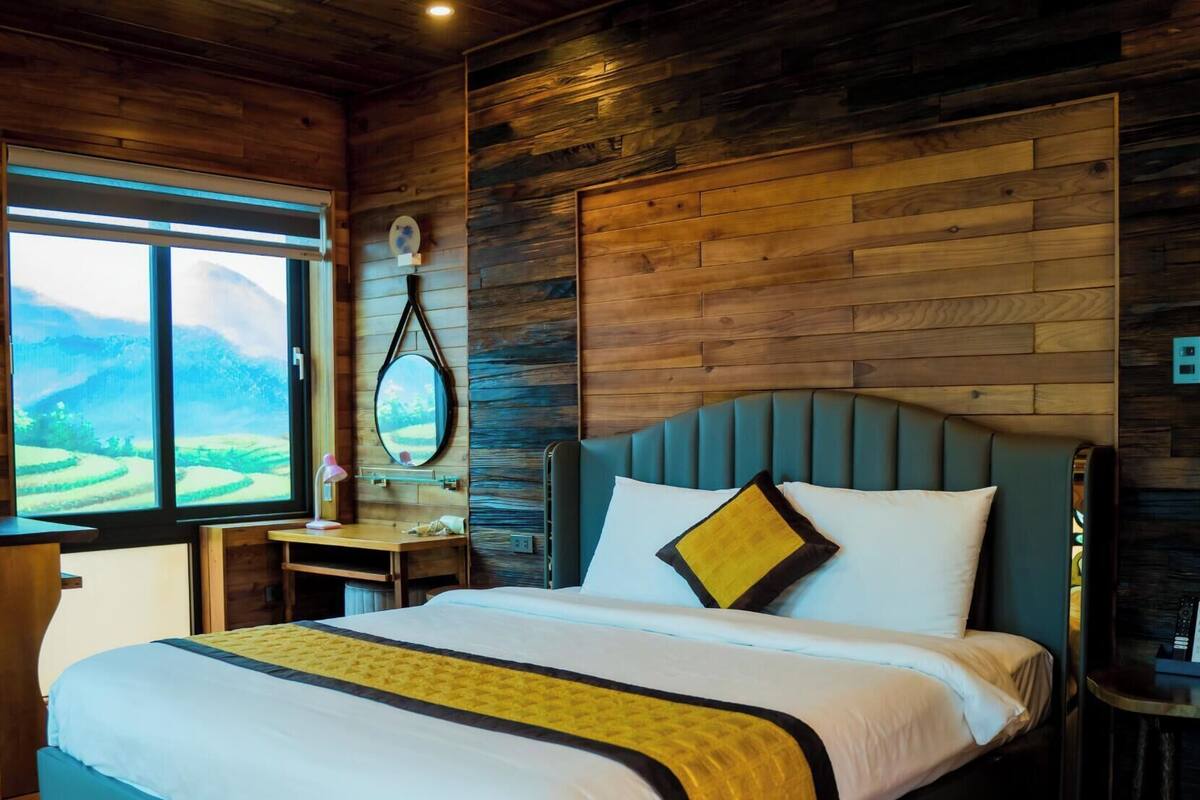 Un dormitorio con una cama grande, una mesita de noche, un espejo y una ventana con vistas al paisaje.