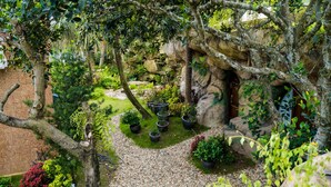 Ein Garten mit Kiesweg, Kübelpflanzen und einer Steinmauer.