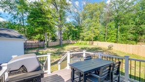 A deck with a grill, a table, and chairs.