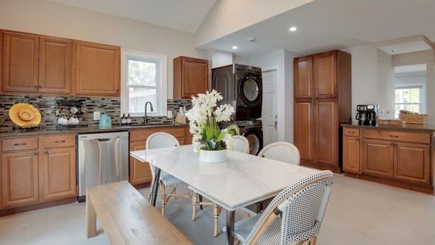 A modern kitchen with wooden cabinets, a stainless steel dishwasher, a built-in oven, and a coffee station.