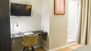 A hotel room with a desk, chair, television, and a door. - GuestReady - Casa das Arcadas - Room 10 (Ponta Delgada)