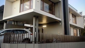 Une maison moderne à deux étages, dotée d’un toit plat, de grandes fenêtres et d’une clôture en bois.