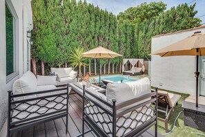 Eine Terrasse mit Gartenmöbeln, einem Pool und hohem Baumbestand im Hintergrund.