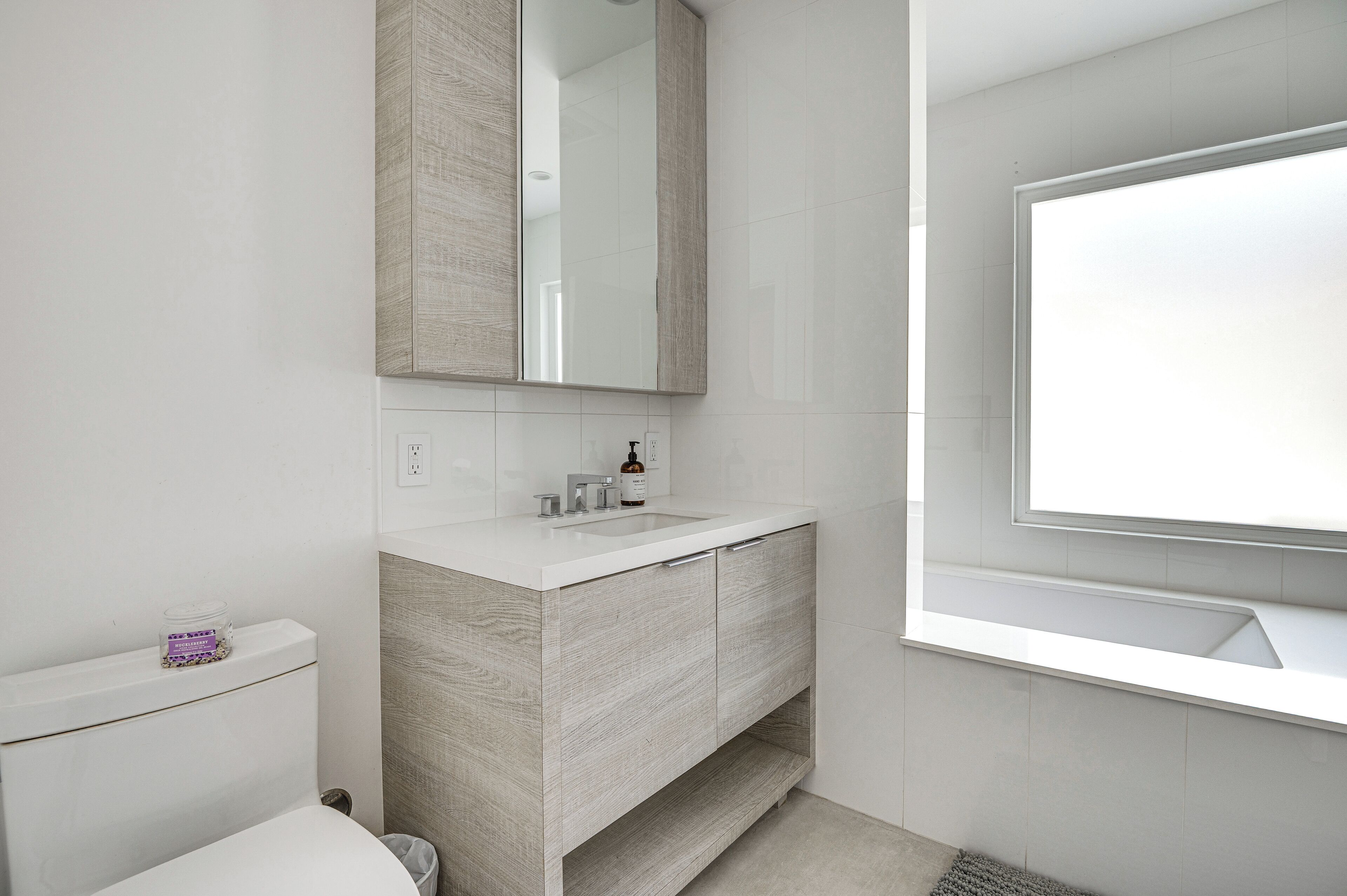 Une salle de bain moderne avec un meuble-lavabo blanc, un miroir et des toilettes.