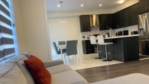 Una cocina moderna con armarios oscuros, un refrigerador de acero inoxidable y una encimera blanca.