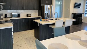Una cocina moderna con armarios oscuros, un refrigerador de acero inoxidable, un microondas y un tostador.