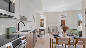 A modern kitchen with a Bosch range, a dining area with a marble table, and a view of a brick building outside. - Gallery Flat by Dupont Circle Large patio & Grill (Washington)